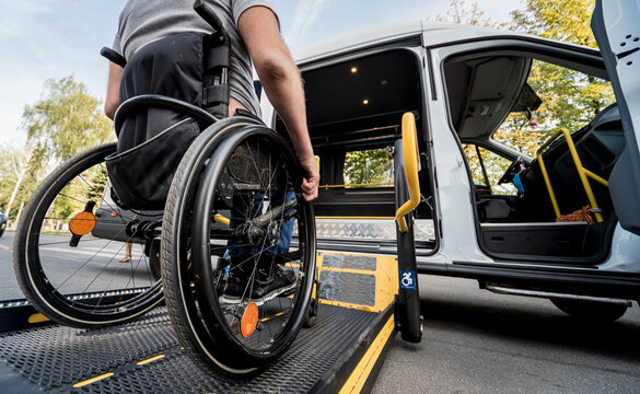 A man in a wheelchair moves to the lift of a specialized vehicle 