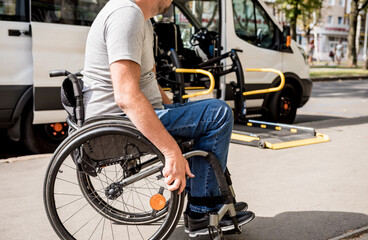 A man in a wheelchair moves to the lift of a specialized vehicle 