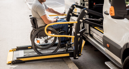A man in a wheelchair on a lift of a vehicle for people with disabilities