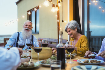 Happy senior friends having fun dining together on house patio - Elderly lifestyle people and food concept