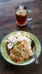 Kupat Tahu, a traditional Javanese Indonesian food containing kupat, fried tofu, cabbage, bean sprouts, and peanut sauce. There is a glass of iced tea