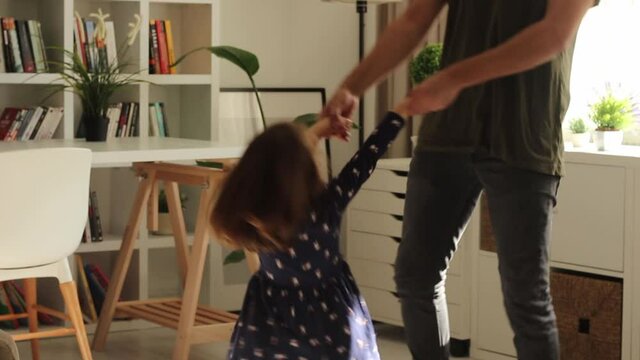 Little girl is dancing at home and having nice time with her father.