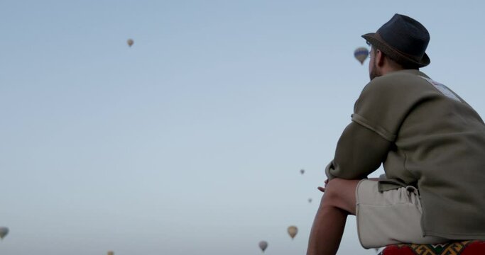 Young tourist man watching a hot air balloon tour in Cappadocia.