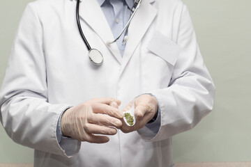 A doctor with a stethoscope rolling a green medical cannabis joint for treatment