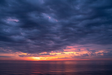 Naklejka na ściany i meble Beautiful Sunrise over the Ocean with Dramatic Clouds