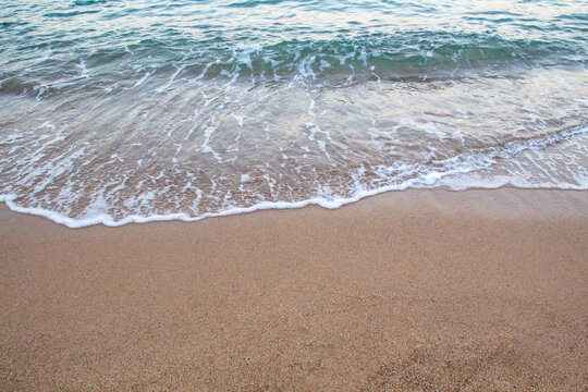 The beach with sea waves running on the sand. Beautiful view on the waves