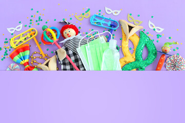 Fototapeta premium Purim celebration concept (jewish carnival holiday) over purple background. Top view, Flat lay. Coronavirus prevention concept, medical mask and sanitizer gel