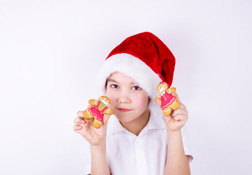 a boy in a Santa Claus hat holds Christmas gingerbread on a white background
