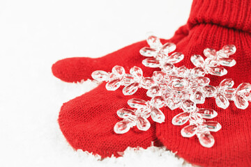 One crystal Christmas snowflake on red knitted mittens. Merry Christmas and Happy New Year greeting card or banner with copy space