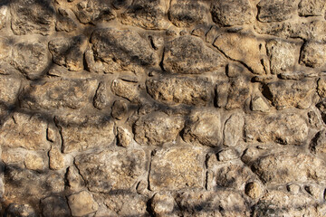 Full frame photo of old stone wall with tree shadows. Antique stone wall background.