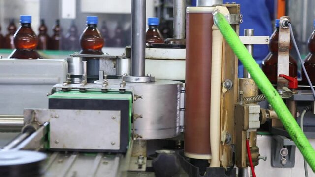 Production and bottling of beverages carbonated lemonade, soda or beer in plastic bottles on automatic conveyor on industrial plant

