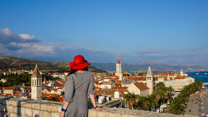 Girl with red hat standing at Tower Kamerlengo overlooking the Trogir Old Town