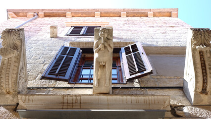 Detail of a building with a statue of a naked man playing on a flute, old town, Korcula, Croatia