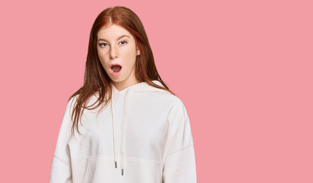 Young read head woman wearing casual sweatshirt scared and amazed with open mouth for surprise, disbelief face