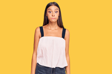 Young hispanic woman wearing casual clothes puffing cheeks with funny face. mouth inflated with air, crazy expression.