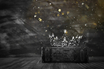 low key image of beautiful queen/king crown on old book. vintage filtered. fantasy medieval period. black and white