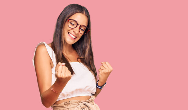 Young hispanic woman wearing casual clothes and glasses celebrating surprised and amazed for success with arms raised and eyes closed. winner concept.