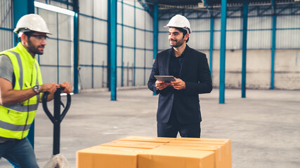 Factory workers deliver boxes package on a pushing trolley in the warehouse . Industry supply chain management concept .