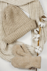 Fototapeta na wymiar female winter knitted accessories. woolen scarf, mittens, beanie hat and cotton buds flat lay. top view of beige warm knit apparel