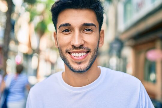 Young latin man smiling happy walking at the city.