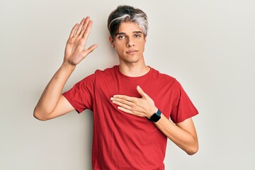 Young hispanic man wearing casual clothes swearing with hand on chest and open palm, making a...
