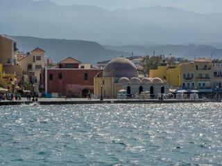 A view across Chania harbour, Crete with the backdrop of the White Mountains in the distant haze on a bright sunny day