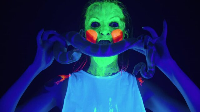Video of girl with scary painted face in ultraviolet light holding snake
