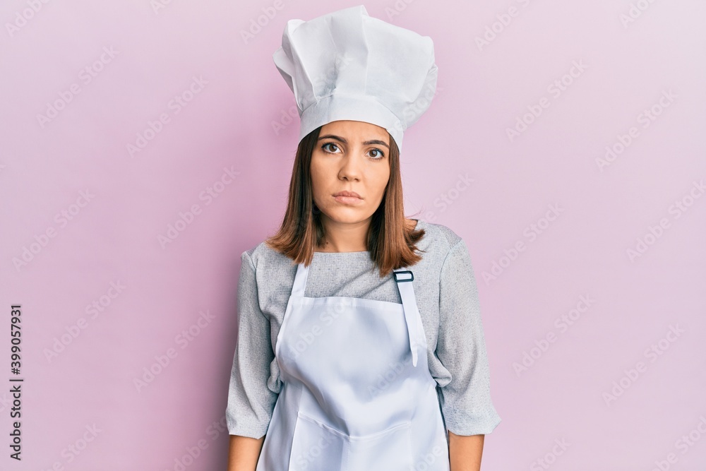 Sticker Young beautiful woman wearing professional cook uniform and hat relaxed with serious expression on face. simple and natural looking at the camera.