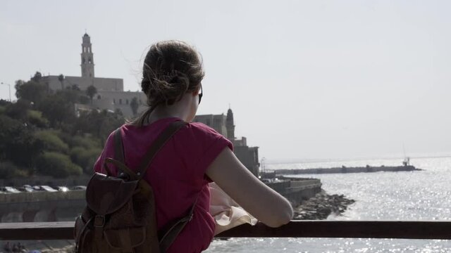 Alone In Thought. Rear View shot of woman watching at the ocean sea while relaxing and thinking. Female tourist on vacation tranquill dreamlike and carefree
