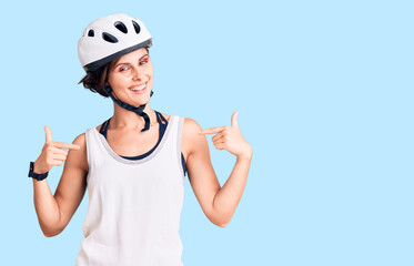 Beautiful young woman with short hair wearing bike helmet looking confident with smile on face, pointing oneself with fingers proud and happy.
