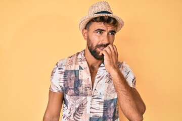 Young hispanic man wearing summer hat looking stressed and nervous with hands on mouth biting nails. anxiety problem.