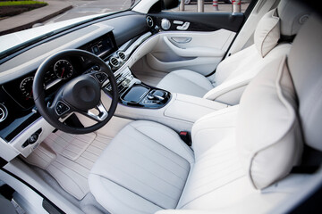 Modern interior of the car - steering wheel and dashboard, front seats with seat belts. white...