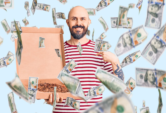 Young handsome man holding delivery pizza box pointing finger to one self smiling happy and proud
