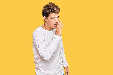 Handsome caucasian man wearing casual white sweater hand on mouth telling secret rumor, whispering malicious talk conversation