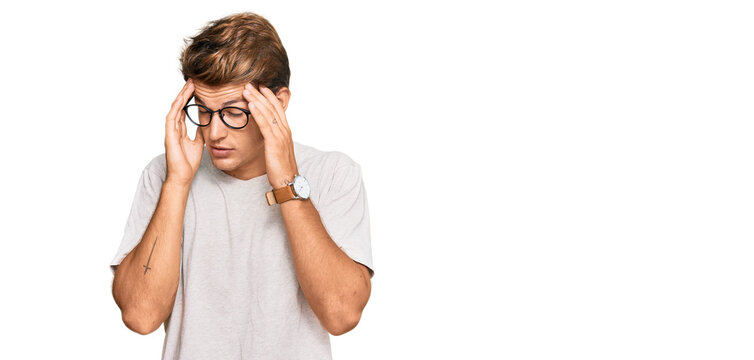 Handsome caucasian man wearing casual clothes and glasses with hand on head, headache because stress. suffering migraine.
