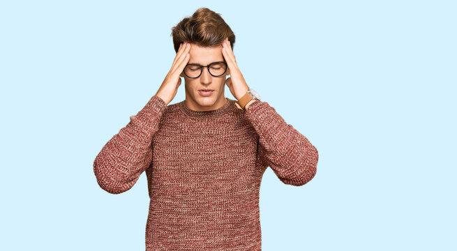 Handsome caucasian man wearing casual sweater and glasses suffering from headache desperate and stressed because pain and migraine. hands on head.