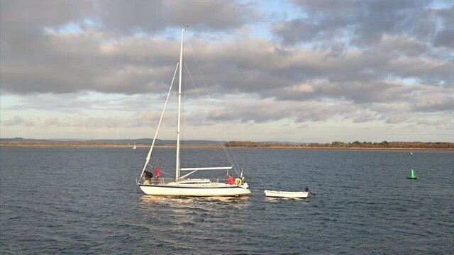 Yacht heading out from East Head near West Wittering in West Sussex with no sail but under power in the late afternoon sun.