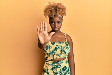 Young african woman with afro hair wearing summer dress doing stop sing with palm of the hand....