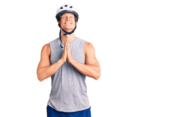 Young handsome man wearing bike helmet begging and praying with hands together with hope expression on face very emotional and worried. begging.