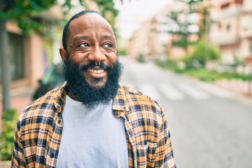 Handsome modern african american man with beard smiling positive standing at the street