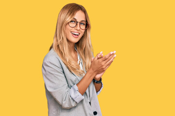 Beautiful blonde young woman wearing business clothes clapping and applauding happy and joyful, smiling proud hands together