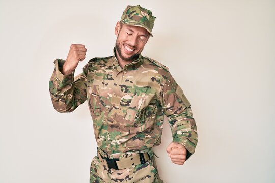 Young caucasian man wearing camouflage army uniform dancing happy and cheerful, smiling moving casual and confident listening to music
