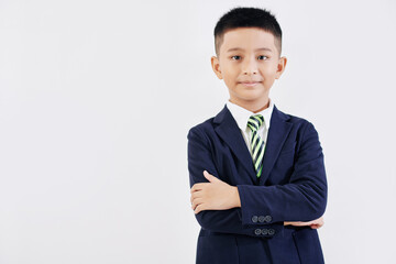 Portrait of smiling confident schoolboy in school uniform folding arms and looking at camera