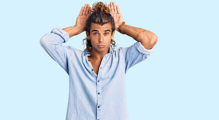Young hispanic man wearing summer style doing bunny ears gesture with hands palms looking cynical...