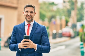 Young caucasian businessman smiling happy using smartphone at the city.