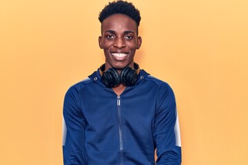 Obraz premium Young african american man wearing sportswear and headphones with a happy and cool smile on face. lucky person.