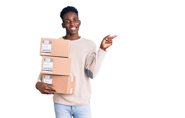 Young african american man holding delivery package smiling happy pointing with hand and finger to the side