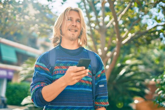 Young scandinavian student man smiling happy using smartphone at the park.
