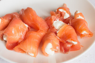 Plating food of smoked salmon filled with cream cheese on a white plate.Appetizers and fish.
