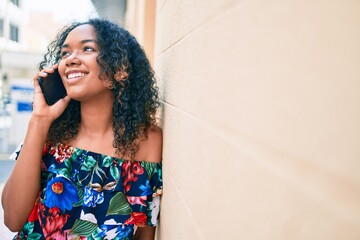 Young african american woman with curly hair smiling happy outdoors speaking on the phone